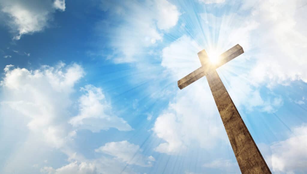A wooden Christian cross with bright sun and clouds. - You Are Not A Nobody, You Are Chosen