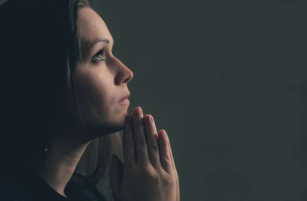 A woman holds her hands in prayer - Bible scriptures for loneliness