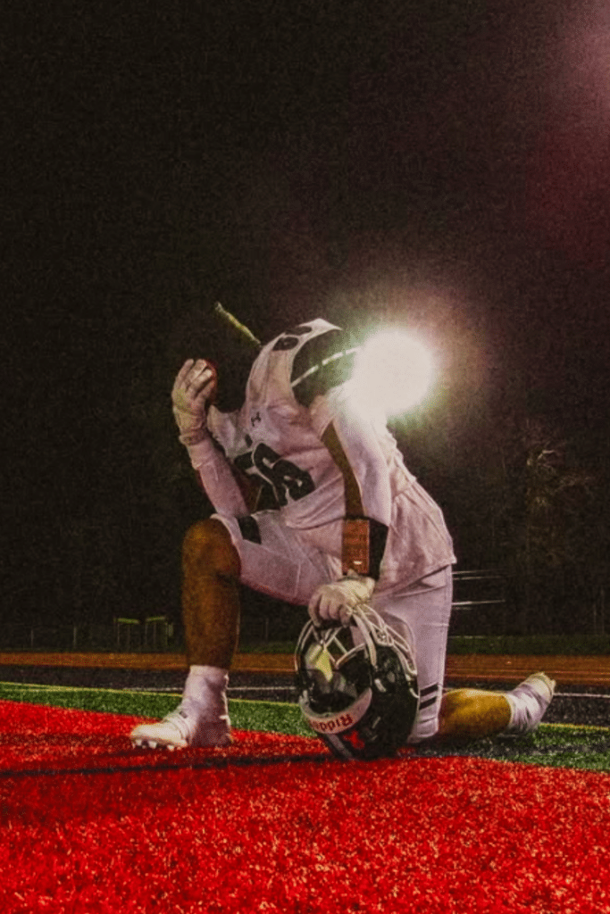 Noah Schreiner on sidelines praying. Student athlete - football player for Shenendehowa High School.